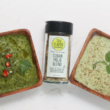 Two wooden bowls one of chimirruchi and one of cilantro lime creme with a jar of Cuban Mojo Blend on a white background